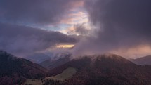 Fast clouds moving in autumn forest mountains at golden sunrise Time lapse
