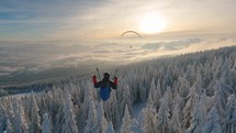 Freedom of paragliding flying above winter forest in misty alpine mountains, Adrenaline outdoor adventure
