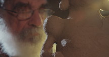 Old sculptor working on a clay sculpture in his small studio