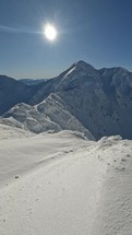 Vertical panorama of frozen winter mountains in sunny alps landscape ideal for outdoor adventure activity
