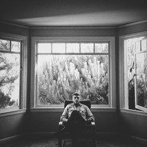 man sitting in a chair in front of a window