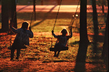 kids swinging at sunset 