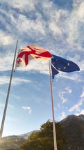 Vertical video state flags of Georgia and European union waving in wind towards blue sky in sunny day

