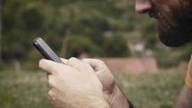 man scrolling through his phone reading a Bible app 