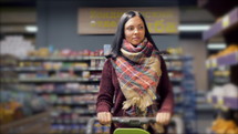 Customers shopping in supermarket, focus on woman with shopping cart. Slow motion.