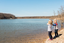 children skipping rocks on a riverbank 