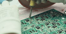Worker inspecting and soldering electronic boards