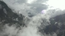 Aerial view flying through clouds in the mountains.