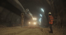 Construction workers supervising heavy machinery during tunnel construction work