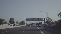 Driving under freeway signs that lead to different places.