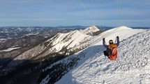 Adrenaline paragliding flying adventure above snowy alpine mountains nature in sunny winter
