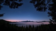 Romantic Blue Starry night sky with stars motion over forest mountains in foggy valley wild Astronomy Landscape Time-lapse
