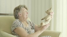 Senior woman holding old teddy bear themes of reminiscing memories childhood nostalgia