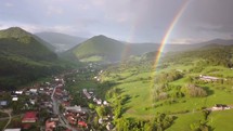 Beautiful rainbow over small village in fresh green nature Aerial view
