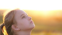 Profile of young girl looking up at sunset sky. Kid wants a dream come true portrait at sunset. baby daughter silhouette dreaming of a happy childhood. Girl looks-up, passionate dreamer.