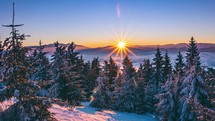 Time lapse of winter sunrise in frozen forest mountains.