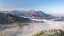 Fly above foggy clouds in autumn forest mountains in morning nature landscape Time lapse
