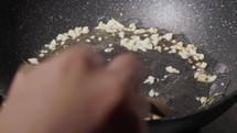 Chef Frying Garlic with Rosemary In Oil On Non-stick Pan. - close up shot
