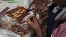 Woman putting a small piece of leather into a metal buckle 