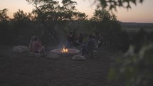 young people sitting around a fire pit 