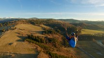 Paragliding flying freedom above autumn nature at golden sunrise
