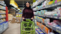 Customers shopping in supermarket, focus on woman with shopping cart. Slow motion.