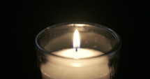 Slow motion close up footage of a white candle on a dark background