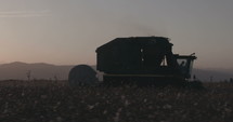Cotton harvesting machine during plowing a cotton field at sunset.