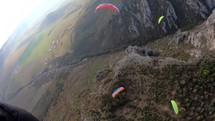 Paragliding friends fly together above rocky mountains.