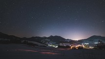 Stars timelapse in blue night sky over alpine nature in winter countryside
