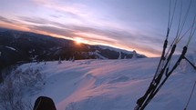 Evening paragliding flight over winter mountains at sunset.
