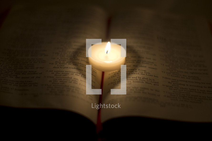 burning votive candle on a Bible