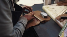 Woman hammering pieces of a leather wallet together