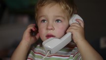 Excited little boy talking over telephone receiver