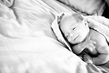 swaddled smiling infant lying on bed