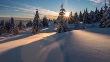 Timelapse of sunset in snowy forest mountains.
