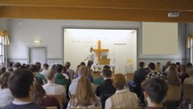 Man preaches or teaches the Bible in a chapel to a group of young adults
