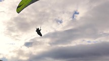 Paraglider on green paragliding wing fly above summer mountains adrenaline adventure freedom
