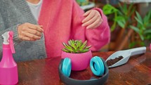 Woman putting headphones on potted plant.