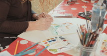 Female artist painting in her studio with water colors and pencils