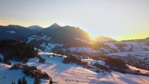 Aerial view of colorful winter sunset over rural countryside in snowy alpine nature landscape