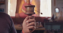 Slow motion of a man spinning a wooden Buddhist prayer wheel.