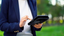 Successful business woman with tablet computer on green park background. 