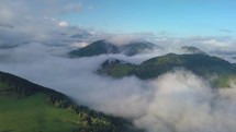 Aerial view above mist clouds in magic country landscape at morning sunrise
