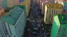]Cityscape with multicolored houses, cars on the street. Top down view, drone video footage
