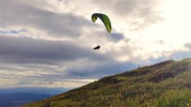 Paragliding freedom adrenaline flying in the sky above grassy mountains
