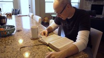 A man reading his Bible in his kitchen 