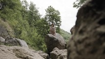 a woman sitting along on a rock 