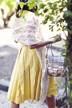 A woman  carrying a basket of eggs in yellow dress summer spring