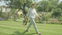 Happy joyful senior caucasian woman twirling walking through her garden themes of retirement gardening active senior carefree
